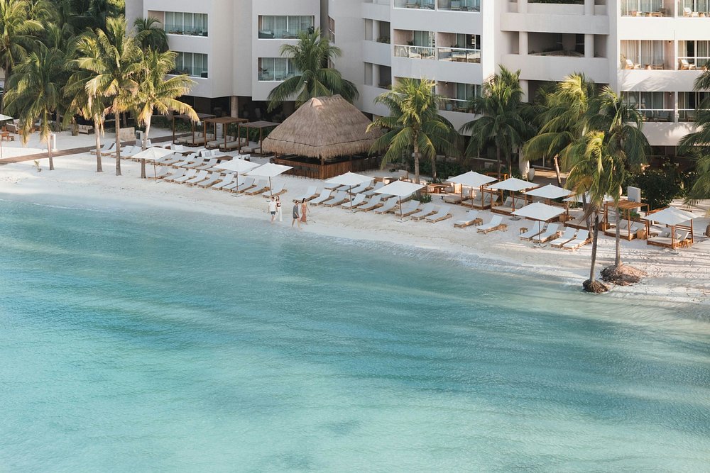 Ariel view of Almare Luxury Resort, Isla Mujeres, Mexico, showing the gentle turquoise Caribbean Ocean surf against the luxury hotel beach chair and day bed assortment.