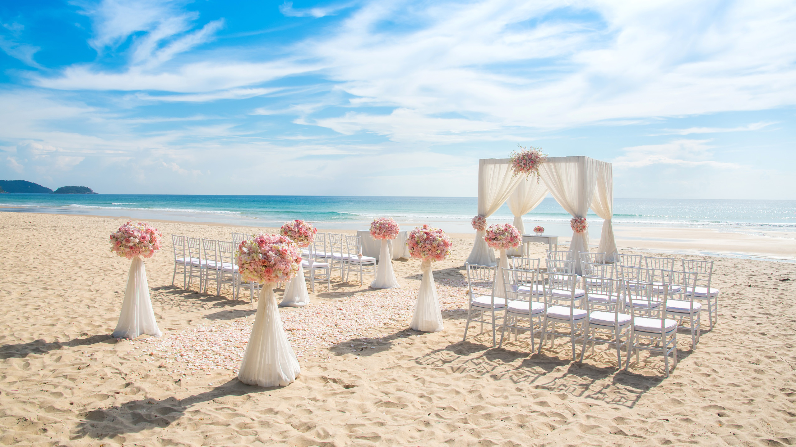Destination wedding in Maldives with traditional ceremonial booth with chairs, flowers and endless turquoise oceans representing unlocking unforgettable experiences